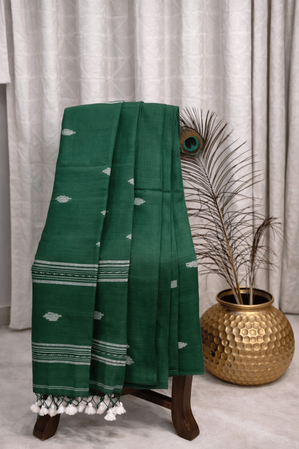 Dark green cotton saree with white ikat motifs, striped border and tassel pallu